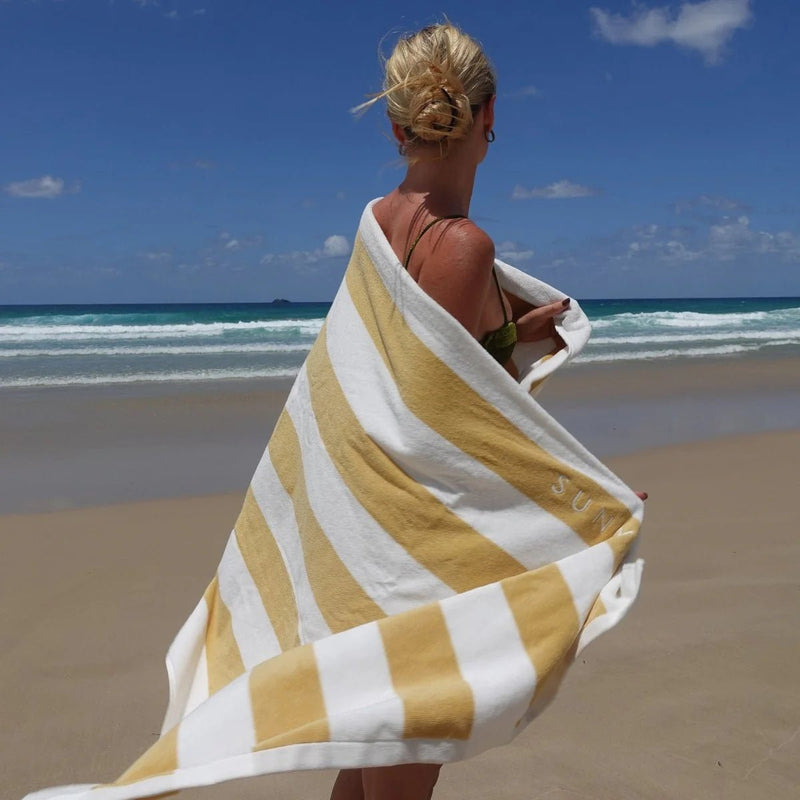 Woman wrapped in a yellow and white striped towel on a beach