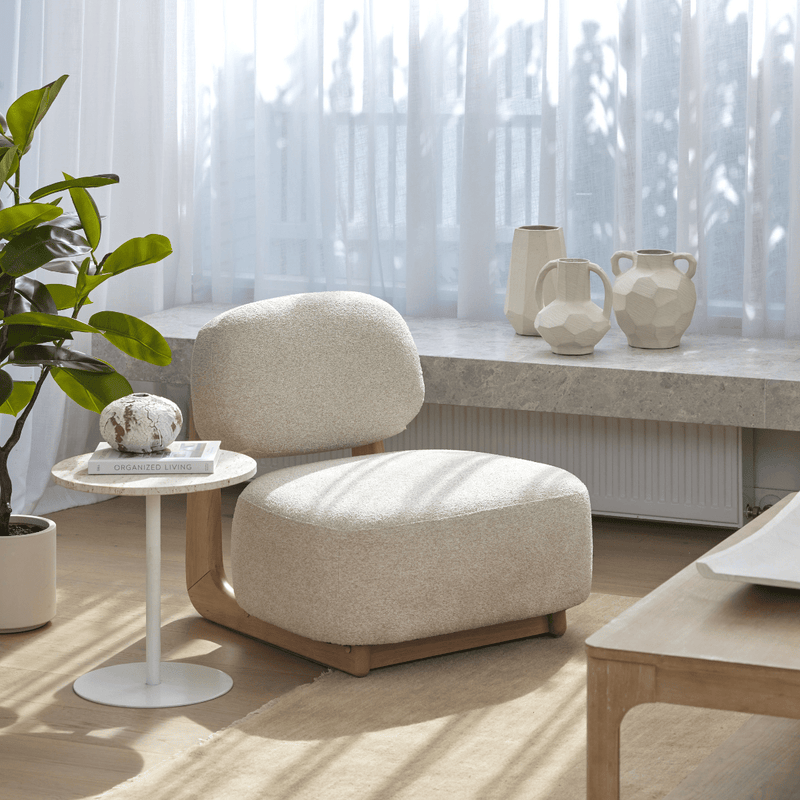 Beige armchair in a modern living room with a table and decorative vases.