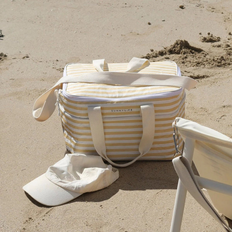 Beige and white striped bag with 'Sunnylife' branding on a sandy beach.