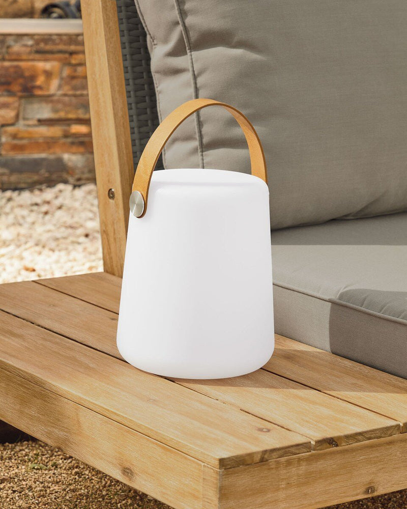 White outdoor lantern with a wooden handle on a wooden surface
