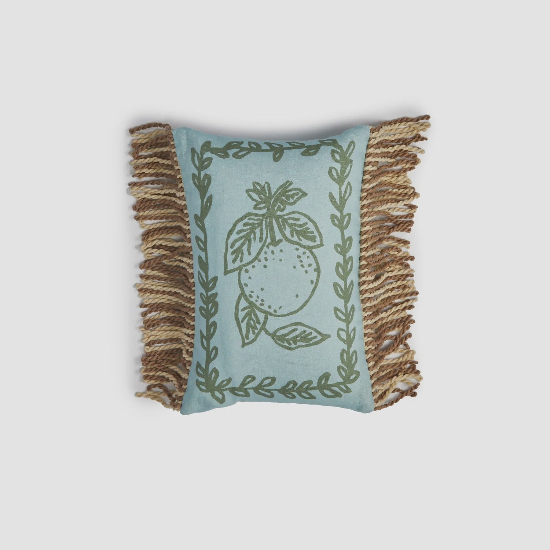 Decorative pillow with fringe and leaf pattern on a light gray background